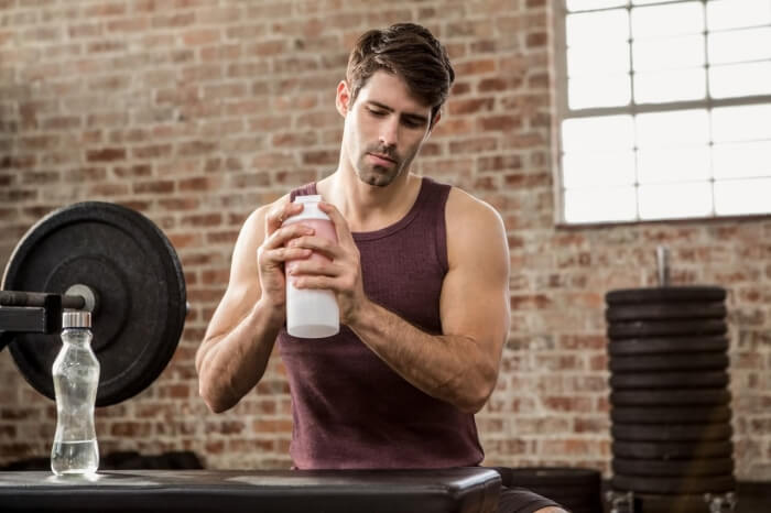 man making a protein shake at the gym