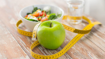 close up of green apple and measuring tape