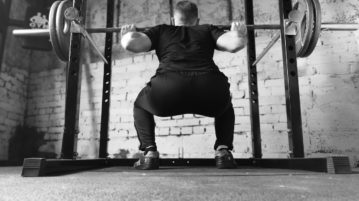 Black and white photo of a man doing squats